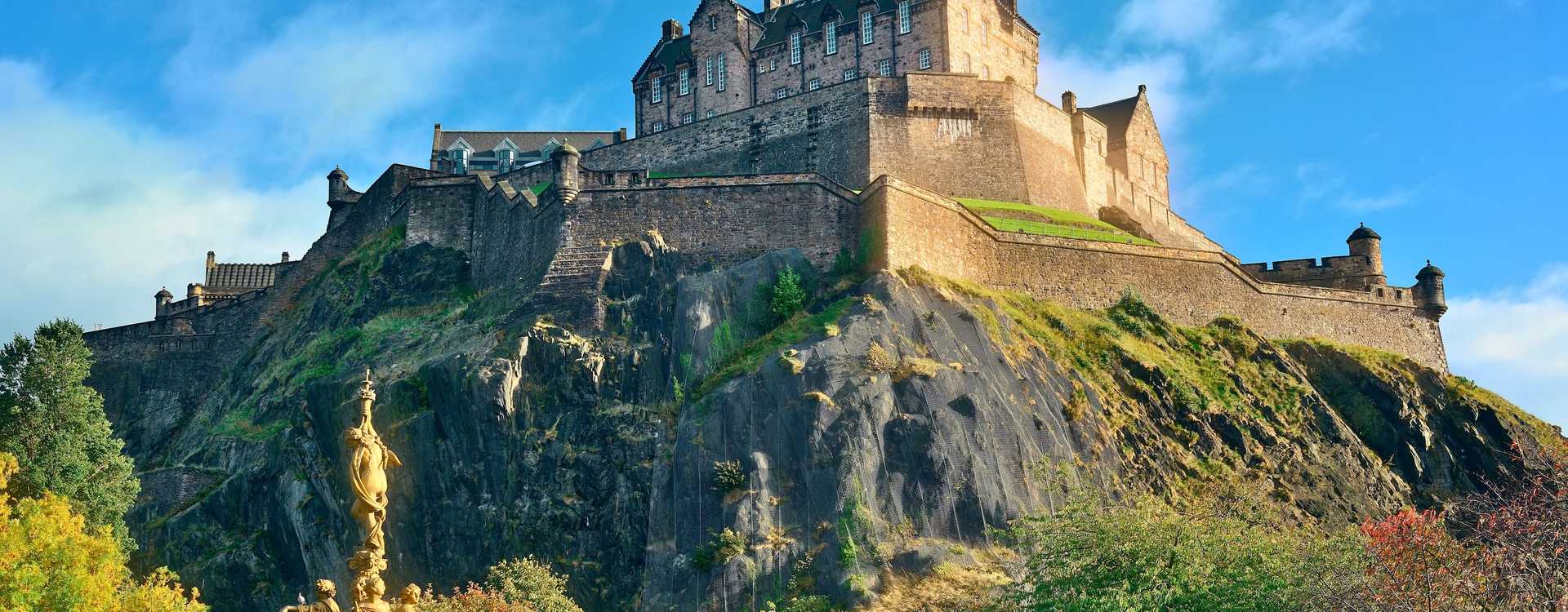 Panoramic view of Edinburgh Castle perched atop the ancient volcanic rock above Princes Street Gardens and the Ross Fountain – Premier asset guide for regional castle tours in 2026
